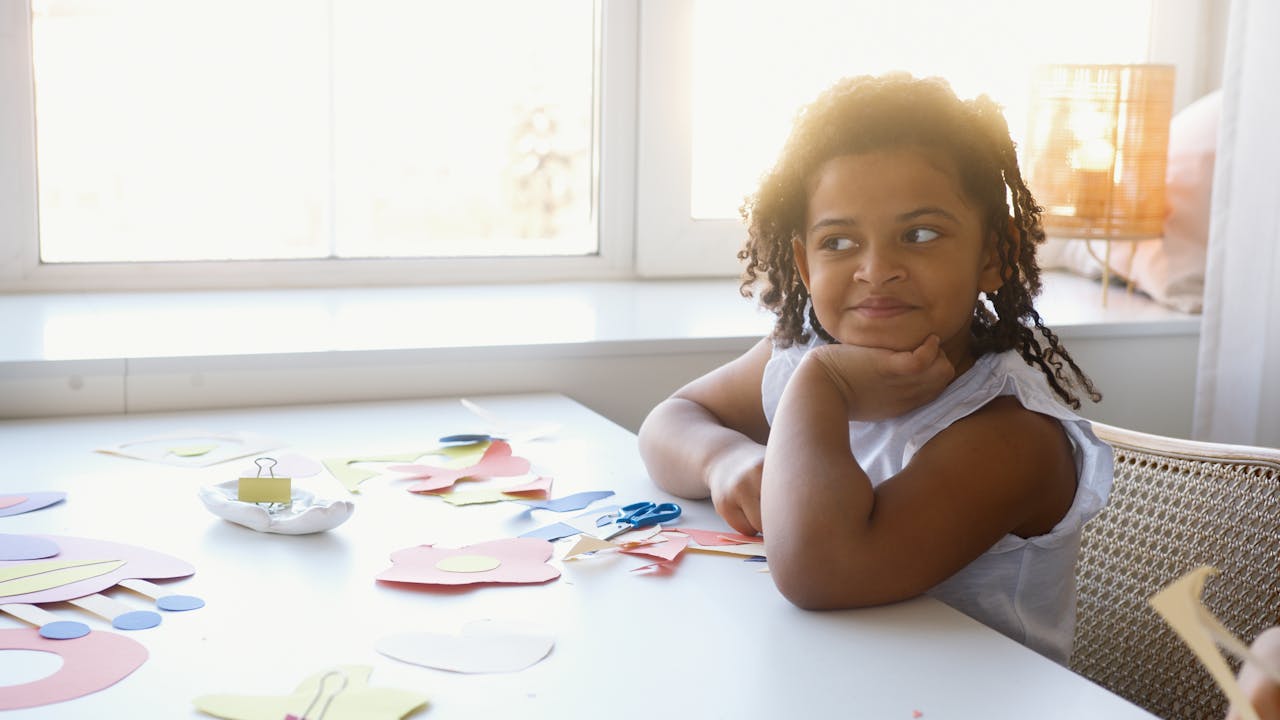 Small girl leaning on a table & smiling - image relates to Mutual funds for Minor Child: Advantages & Disadvantages
